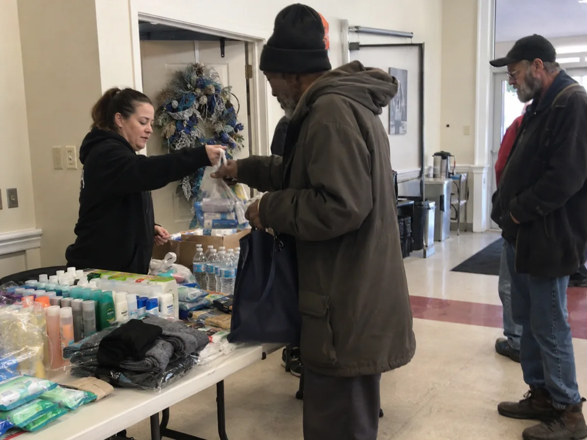 A volunteer distributing hygiene supplies indoors.