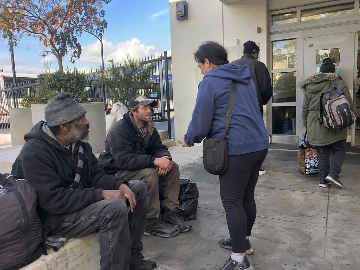 An outreach worker speaking with people outside a transit center.