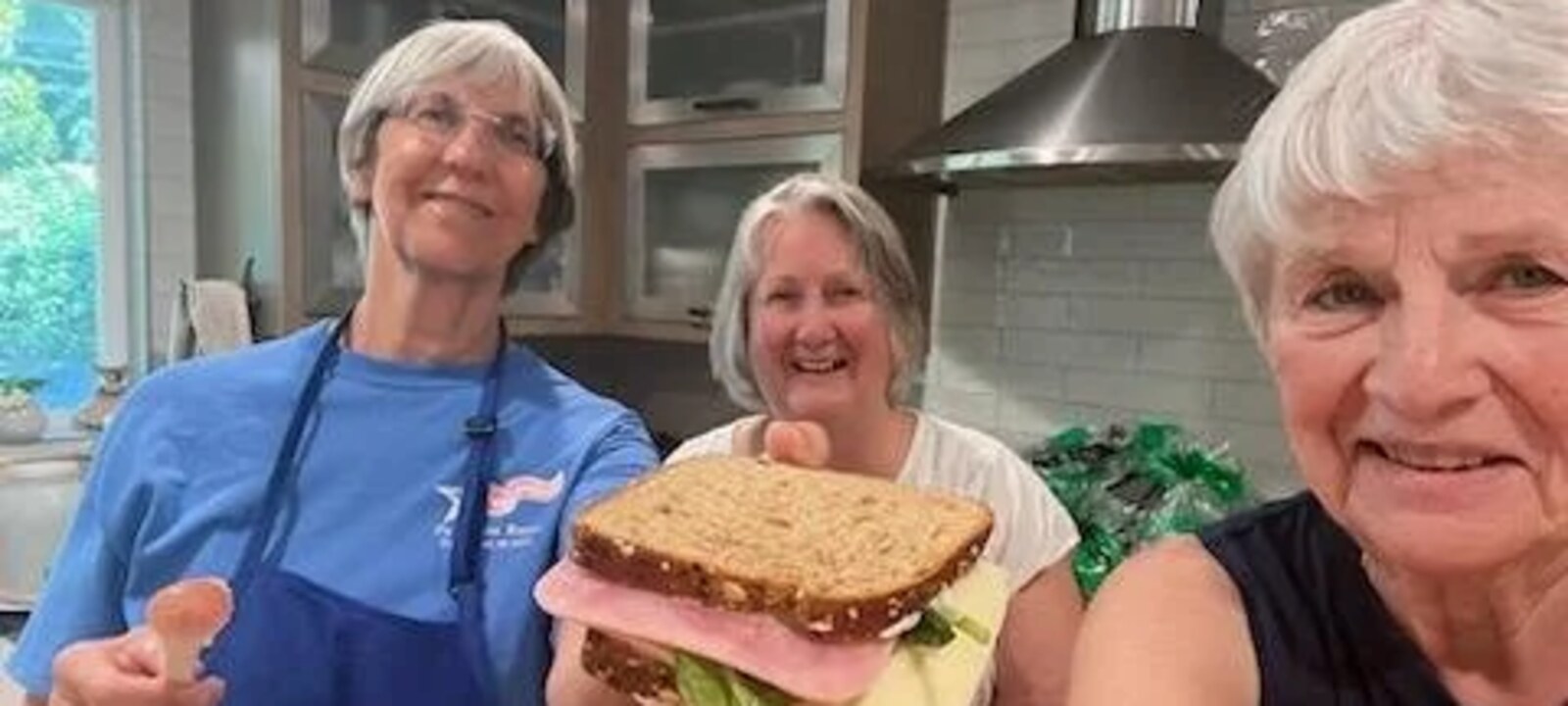 Volunteers smiling while preparing sandwiches.